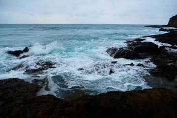Waves on the seaside are splashing on the rocks in a stormy day
