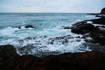Fototapeta na wymiar Waves on the seaside are splashing on the rocks in a stormy day