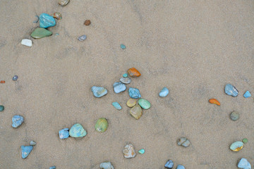 Fototapeta na wymiar Sea stones on sand. Summer beach background. View from above
