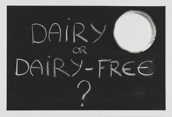 dairy or dairy-free debate, text on blackboard with glass of milk from topdown perspective