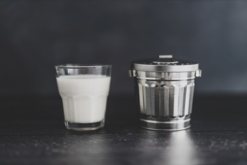 dairy or dairy-free debate, glass of milk with garbage bin