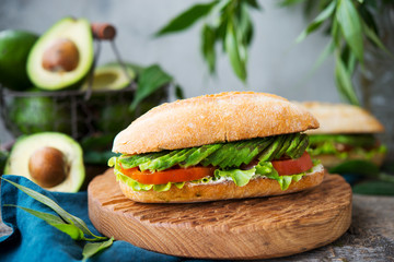 Homemade vegetable sandwich with cream cheese, fresh avocado and tomatoes on a wooden table. Horizontal photo. Selective focus.