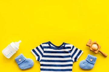 Baby background - blue color. Clothes and accessories for newborn boy on yellow table top-down frame copy space