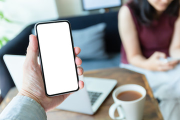 Mockup image blank white screen cell phone.men hand holding texting using mobile on desk at home office. background empty space for advertise text.people contact marketing business and technology 
