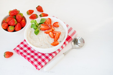 Healthy balanced Breakfast of oatmeal with strawberries and honey on a white background. Horizontal photo with copy space.