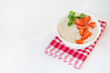 Healthy balanced Breakfast of oatmeal with strawberries on a white background. Horizontal photo with copy space.
