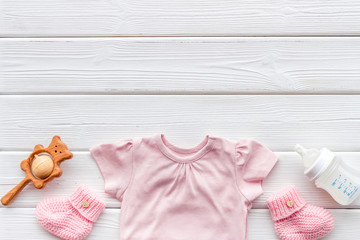 Baby background - pink color. Clothes, booties and accessories for newborn girl on white wooden table top-down frame copy space