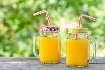 Orange juice in mason jars with straws on wooden table