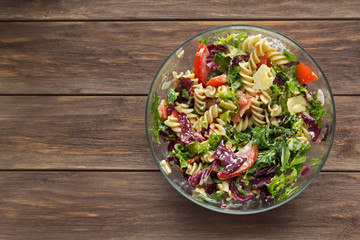 Vegetable salad with pasta and cheese on wooden background. Vegetarian, recipe, culinary, cooking concept. Top view, close-up, copy space