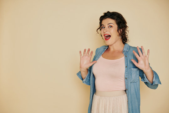 Excited surprised pretty young woman opening mouth when looking at something shoking