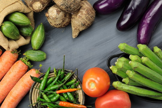 Indian vegetables of Tomatoes, carrots, Yams, Pointed gourd, Green chilies, Methi leaves, cilantro, and egg plants with copy space.