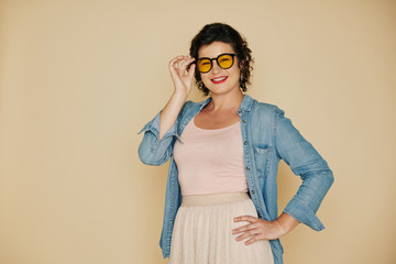 Portrait of pretty smiling woman putting on glasses with yellow lens and looking at camera