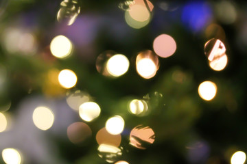Christmas abstract blurred background with bokeh colorful circles. Artificial fir tree with led light garland. Festive holiday background.