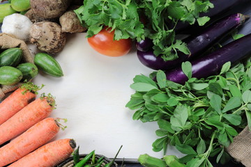 Indian vegetables of Tomatoes, carrots, Yams, Pointed gourd, Green chilies, Methi leaves, cilantro, and egg plants with copy space.
