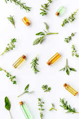 Essential oils and fresh herbs on white background top view pattern