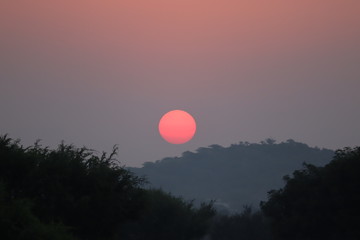 Beautiful blazing sunset landscape at over the meadow and orange sky above it. Amazing summer sunrise as a background