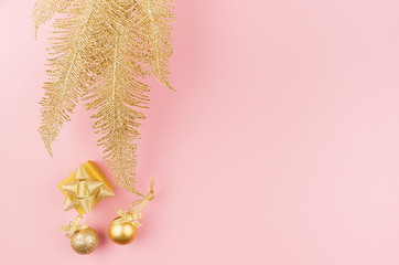 New Year modern stylish background in gold and pink color - golden palm branch, glittering balls, ribbon on pastel pink color, top view, copy space.