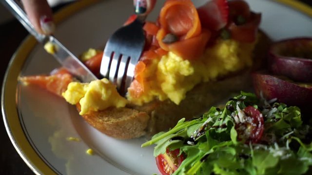 slicing smoked salmon with crumble egg toasted with salad