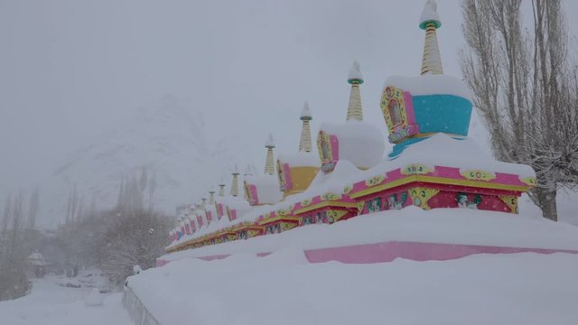snowing in the valley, stupa covered in snow