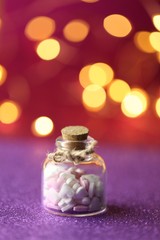  Love concept. Valentine's Day. Bottle with hearts and golden bokeh on a  pink violet background