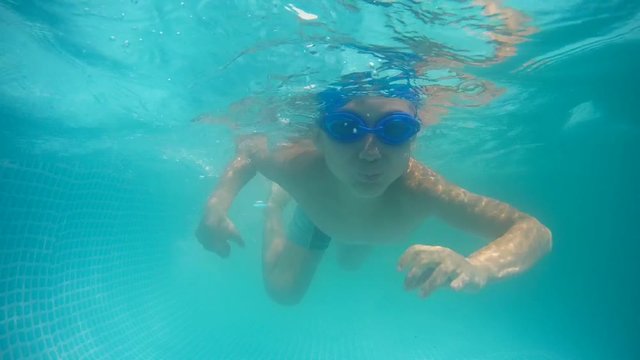 Summer day. The child swims under water in diving goggles. Mobile home-pool
