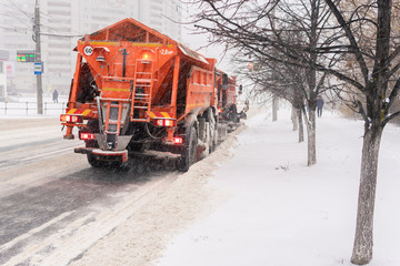 A large snowplow removes snow from the road