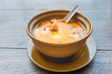 Tom yam kong on wooden table in street cafe