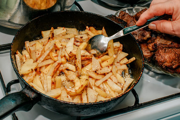 Fried potatoes in a frying pan stir with a spoon