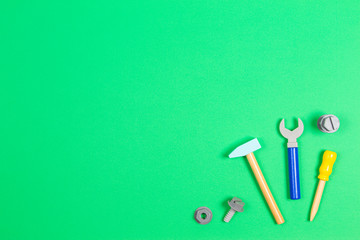 Wooden kids toys screwdriver, plier, bolts, nuts and other construction tools frame on light green background. Top view