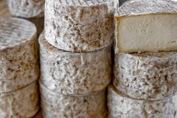 Whole cheese heads and slices in the background. French traditional cheese.