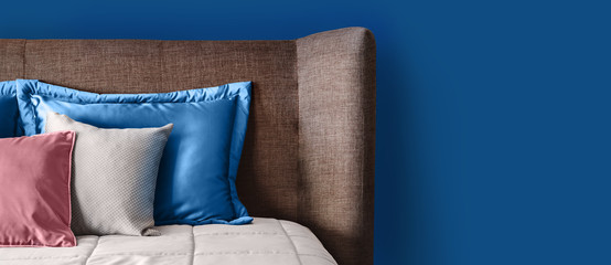 Classic blue color in living interior. Soft Headboard and pillows. Fragment of cozy modern bedroom