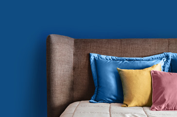 Fragment of cozy modern bedroom in classic blue color. Soft Headboard and pillows