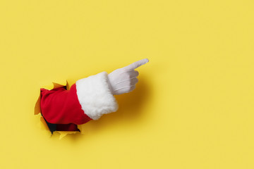 Santa Claus hand presenting your christmas text or product over yellow background