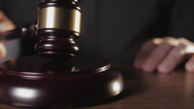 Close - up of the judge knocking three times with a wooden mallet.