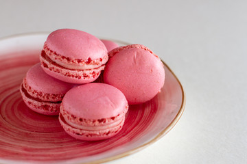 a strawberry macaroon on a coral porcelain plate