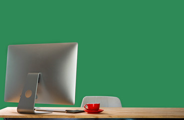 Workspace with computer, keyboard,coffee cup and Mouse with Blank or White Screen Isolated is on the work table at the mountain and Sea green background.