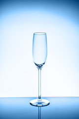 Champagne glass on the light background. Fine cristal glassware concept. Vertical, toned in blue