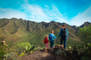 mother with kids hiking in mountains, family travel in nature
