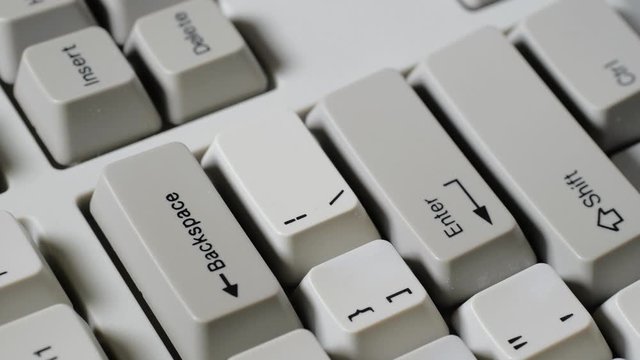 Finger presses BACKSPACE button on keyboard