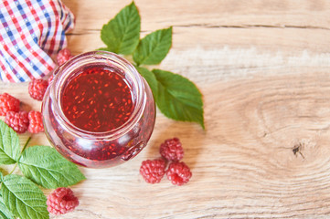 homemade raspberry jam with fresh raspberries on wooden table. top view, selective focus