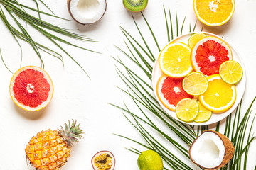 Tropical fruits and palm leaves on a white background.