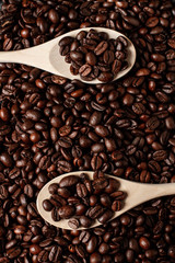 Wooden spoon with coffee on a coffee beans background. Close up. Dark concrete. Top view. Empty space.