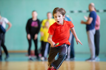 Fototapeta premium Child in the gym. A schoolboy in a physical education lesson. Relay race in elementary school. The boy goes in for sports. Children's training. Sports Day.