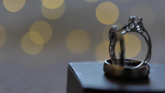 Slow slider passed engagement rings on box bokeh lights