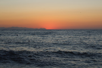 Fototapeta premium the sun setting behind the promontory with the sea in the foreground