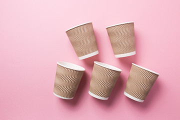 Paper cup for hot coffee or tea on a pink isolated background.