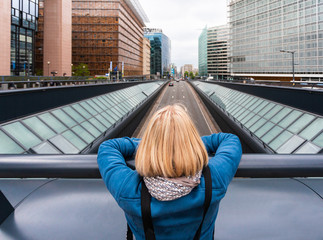 Fototapeta na wymiar A woman stands on a bridge with her back to the camera against the background of a modern office quarter, Belgium