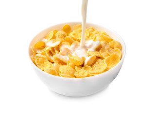 Pouring milk into bowl with corn flakes on white background
