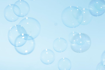 Transparent soap bubbles float in the air on a blue background