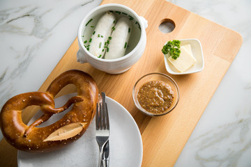 Münchener Weißwurst in Terrine mit bayrischer süßen Senf, Brezel und Butter auf Holz Brett